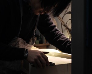 zeyu li working on a guitar with plane